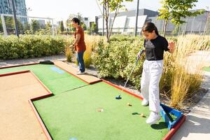 niños jugando golf dentro patio de recreo artificial césped actividad juego para niños foto