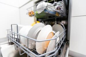 Open dishwasher with clean dishes in the white kitchen photo