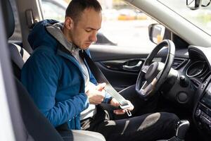 transportation and vehicle concept - man fastening seat belt in car photo