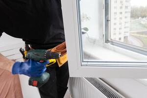 Young repairman fixing window frame in room at daytime photo