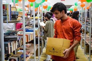 Delhi, India, February 17 2024 - Various age group people reading variety of Books on shelf inside a book-stall at Delhi International Book Fair, Books in Annual Book Fair at Bharat Mandapam complex photo