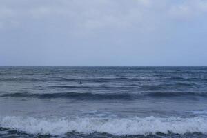 a person flying a kite in the ocean photo