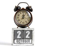 October 22 on wooden calendar with alarm clock white background. photo