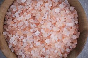 Wooden cup with pink Himalayan salt in closeup. photo