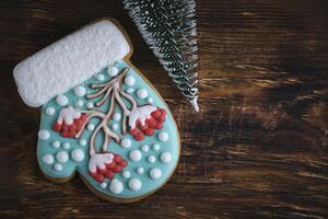 caprichoso mitón conformado Navidad galletas, serbal árbol Formación de hielo, Nevado acentos, en un rústico de madera fondo. foto