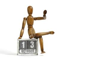 October 13, wooden calendar with mannequin sitting on it on white background. Calendar date. photo