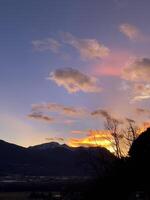 un puesta de sol terminado un montaña rango con nubes foto