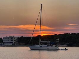 a sailboat is anchored in the water at sunset photo