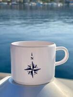 a coffee cup with a compass on it sitting on a boat photo