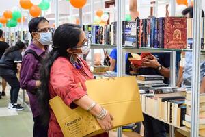 Delhi, India, February 17 2024 - Various age group people reading variety of Books on shelf inside a book-stall at Delhi International Book Fair, Books in Annual Book Fair at Bharat Mandapam complex photo