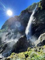 a waterfall is shown in the sun with a blue sky photo