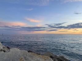 a view of the ocean at sunset from a rocky shore photo