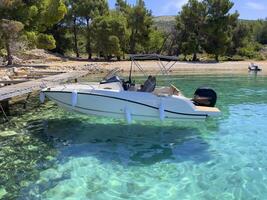 a motor boat docked in clear water near a dock photo