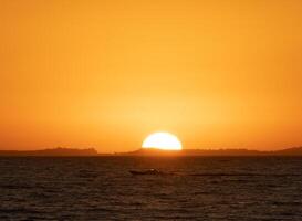 a boat is out on the ocean at sunset photo