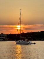 a sailboat is anchored in the water at sunset photo