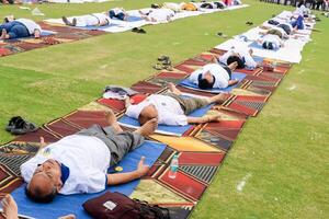 New Delhi, India, June 21, 2023 - Group Yoga exercise session for people at Yamuna Sports Complex in Delhi on International Yoga Day, Big group of adults attending yoga class in cricket stadium photo