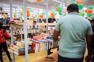 Delhi, India, February 17 2024 - Various age group people reading variety of Books on shelf inside a book-stall at Delhi International Book Fair, Books in Annual Book Fair at Bharat Mandapam complex photo