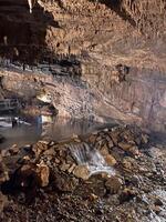 a cave with water flowing through it and people standing around photo