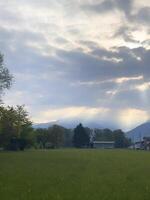 a field with a house and mountains in the background photo