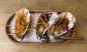 three oysters on a wooden tray with a knife and fork photo