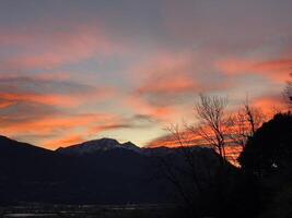 un puesta de sol terminado el montañas con un rojo cielo foto