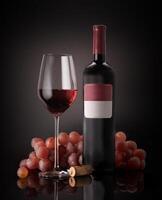 a bottle of red wine and glass of wine with grapes photo