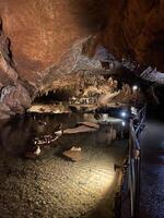 un cueva con agua y un pocos personas en eso foto