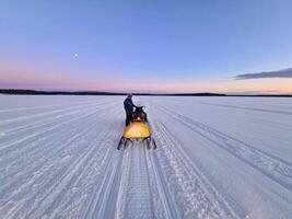 a person on a snowmobile in the middle of a large open field photo