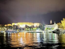 a city at night with boats on the water photo