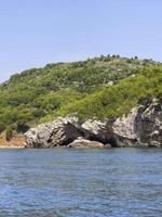 a rocky island with a cave in the middle of the water photo