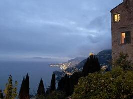 the house is lit up at dusk with the ocean in the background photo