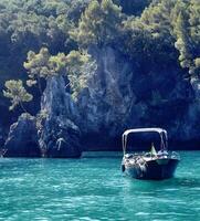 a boat floating in the water near a rocky shore photo