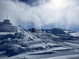 a silhouette of man standing on top of a snow covered mountain photo