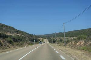 a car driving down a road with a hill in the background photo