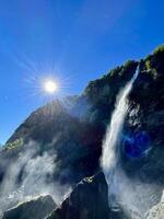 a waterfall with the sun shining over it photo