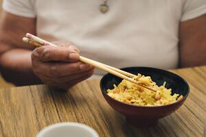 Close-up detail shot of an woman's hands eating rice with chopsticks. photo