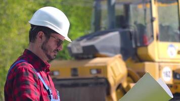 Portrait of the worker in uniforms and white helmet against the background of a road construction site video