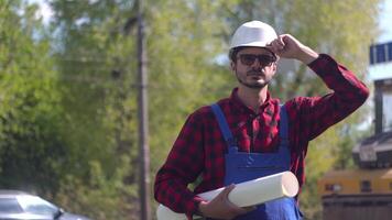 ouvrier dans uniformes et blanc casque contre le Contexte de une route construction site regards à le caméra video