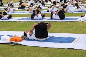 New Delhi, India, June 21, 2023 - Group Yoga exercise session for people at Yamuna Sports Complex in Delhi on International Yoga Day, Big group of adults attending yoga class in cricket stadium photo