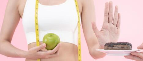 Diet and dieting. Beauty slim female body confuse donut. Woman in exercise clothes achieves weight loss goal for healthy life, crazy about thinness, thin waist, nutritionist. photo