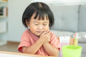 little asian girl presses hand to cheek, suffers from pain in tooth. Teeth decay, dental problems, child emotions and facial expression, oral health care, reducing sweets, fluorine coating photo