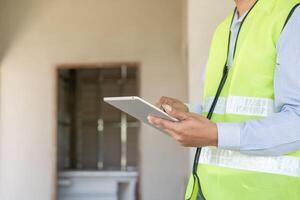 inspector o ingeniero es inspeccionando construcción y calidad garantía nuevo casa utilizando un tableta. ingenieros o arquitectos o contactor trabajo a construir el casa antes de entrega eso terminado a el dueño de casa foto