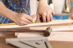 hombre propietario un pequeño mueble negocio es preparando madera para producción. carpintero masculino es ajustar madera a el deseado tamaño. arquitecto, diseñador, incorporado, profesional madera, artesano, taller. foto