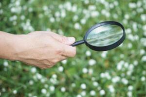 Close up hand hold magnifying glass to inspect tiny things in nature. Concept, exploring, searching, analysis. Study survey and research about ecology  environment. photo