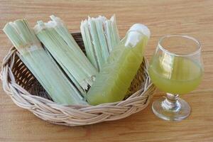 Closeup bottles of fresh sugar cane juice, put on basket. Concept, healthy natural beverage made from agriculture crop. Homemade drinks, has medicinal and herbal photo