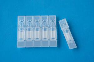 Single use artificial tear lubricant eye drops containers, tubes, isolated on blue background. Concept,medical products for dry eyes or eyes disease treatment. Use under doctor prescription. photo