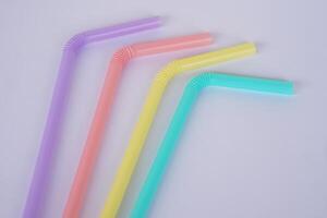 Colorful plastic drinking straws tubes for juice and cocktails, gray background. Concept, single use equipment for drinking, but can use for diy crafts for decoration. photo