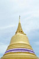 gold pagoda with blue sky and white cloud background. The little turquoise buddha is in front of the gold pagoda photo