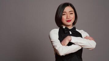 Asian diner employee prepared to serve food at tables, working in hospitality cuisine and catering. Restaurant waitress with apron standing over grey background, gourmet service. Camera B. video