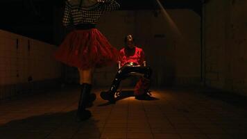 Man in red shirt sitting under moody lighting with a dramatic shadow on the wall. video